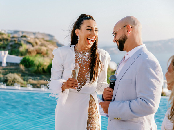 Bride and groom laughing with guests at Santorini celebration
