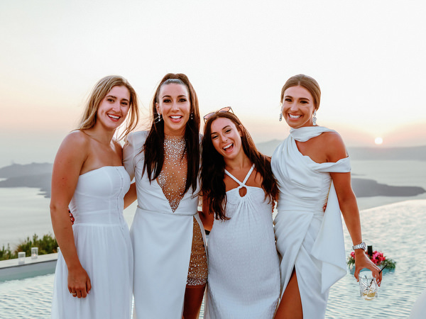 Friends posing together during sunset at Santorini wedding weekend