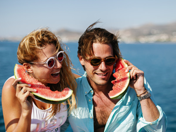 Couple posing playfully with watermelon during Antiparos boat cruise