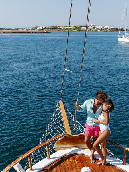 Bride and groom kissing on sailboat during Antiparos cruise