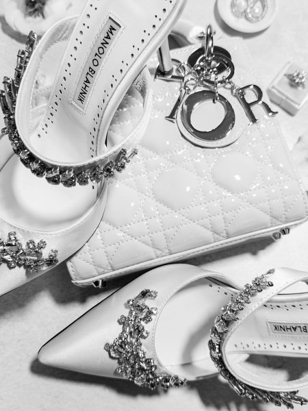 Black and white flat lay of bridal shoes, earrings and wedding accessories