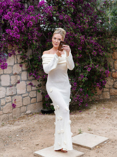 Bride in an elegant wedding dress posing beside colorful bougainvillea in Aegina