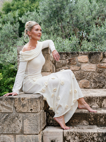 Bride seated on a stone wall in her elegant wedding dress before the ceremony