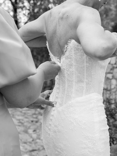 Close-up of a bridesmaid fastening the bride’s wedding gown
