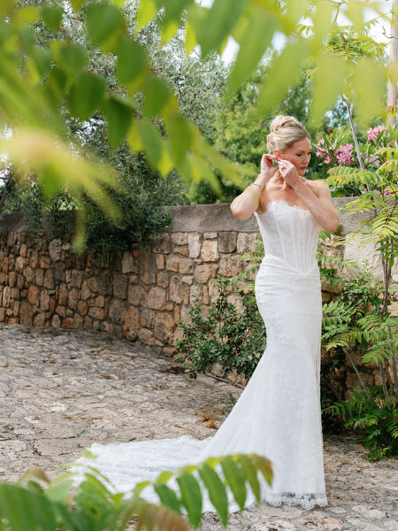 Bride adjusting her earrings among Mediterranean greenery before her Aegina wedding