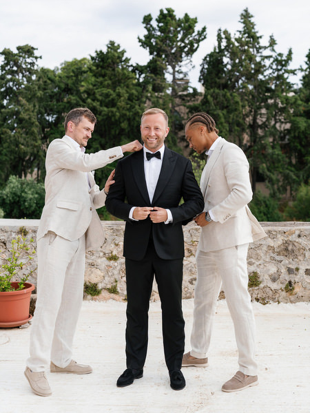 Groomsmen helping the groom with final preparations before the ceremony in Aegina