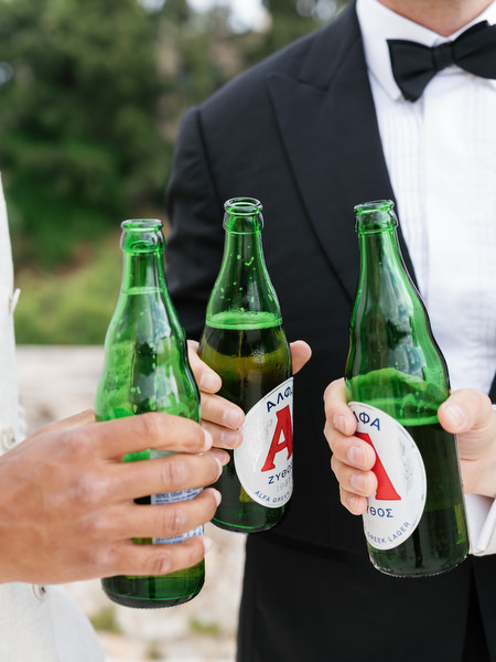 Groom and groomsmen raising beer bottles during relaxed wedding preparations