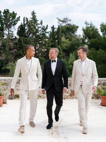 Groom walking with his groomsmen through the grounds of Pyrgos Ralli