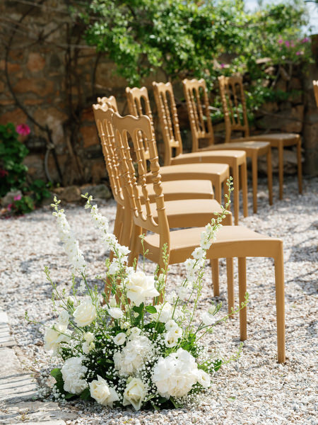 White floral ceremony arrangements and wooden chairs at Pyrgos Ralli in Aegina