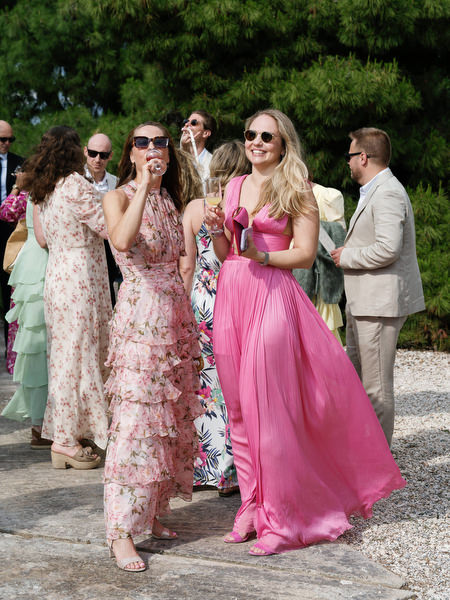 Elegantly dressed wedding guests walking toward the outdoor ceremony at Pyrgos Ralli