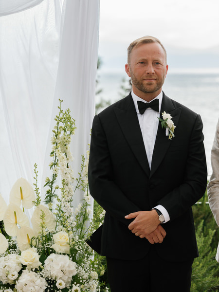 Groom waiting at the altar in a classic black tuxedo before his Aegina wedding ceremony