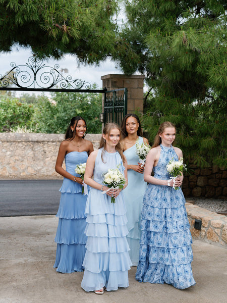 Bridesmaids in blue dresses holding white bouquets before the wedding ceremony
