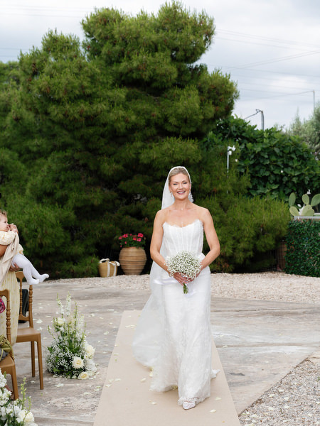 Bride approaching the outdoor wedding ceremony surrounded by Mediterranean greenery