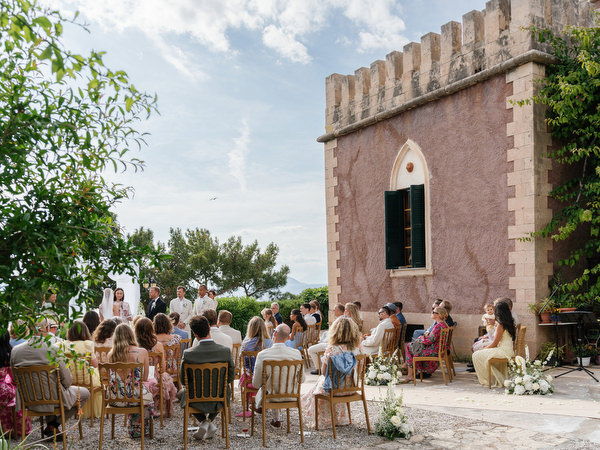Wide view of the outdoor wedding ceremony beside the historic Pyrgos Ralli tower