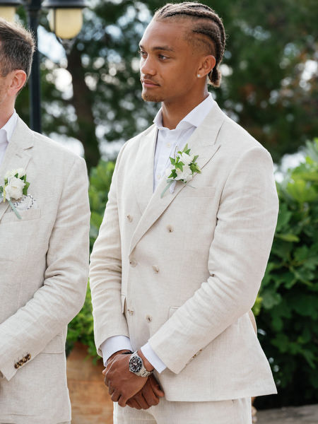 Groomsman listening during the elegant destination wedding ceremony at Pyrgos Ralli