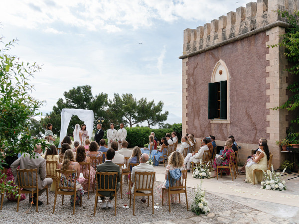 Bride and groom standing beneath a white ceremony arch at their Aegina wedding