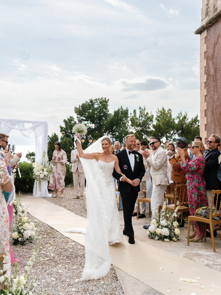 Bride and groom celebrating with raised hands after their Greek island wedding ceremony