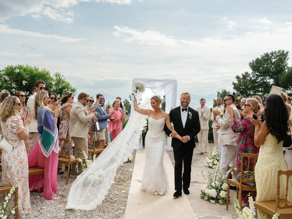 Newlyweds walking through cheering guests after the ceremony at Pyrgos Ralli