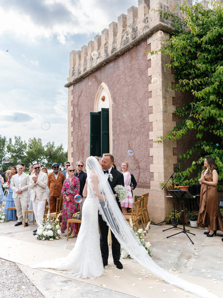 Bride and groom walking past the historic Pyrgos Ralli tower after their ceremony