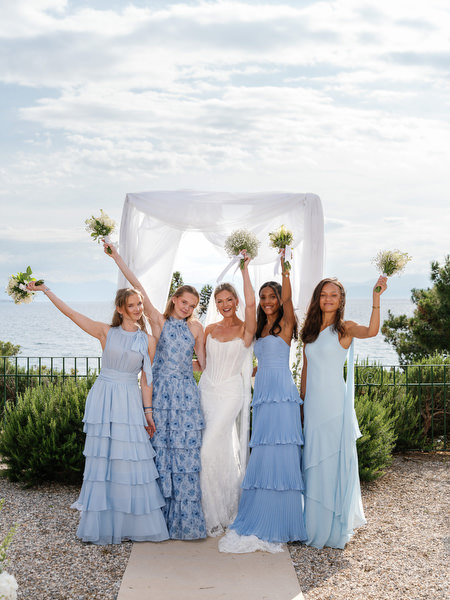 Bride and bridesmaids celebrating with bouquets raised after the Aegina ceremony