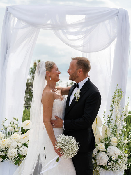 Bride and groom toasting with champagne beneath the white ceremony arch at Pyrgos Ralli