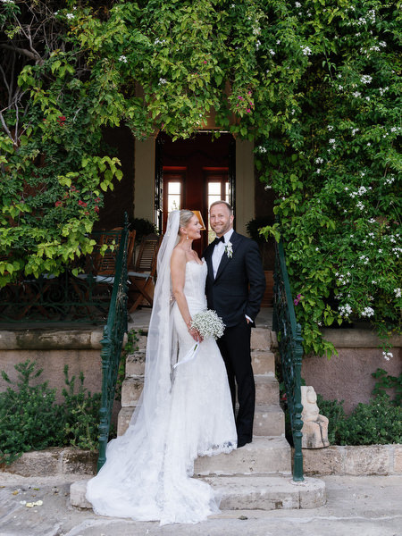 Newlyweds posing beside an ivy-covered doorway at Pyrgos Ralli in Aegina