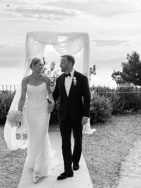 Black and white portrait of the bride and groom walking together after the ceremony