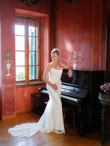 Bride posing inside the red-toned interior of Pyrgos Ralli beside a piano