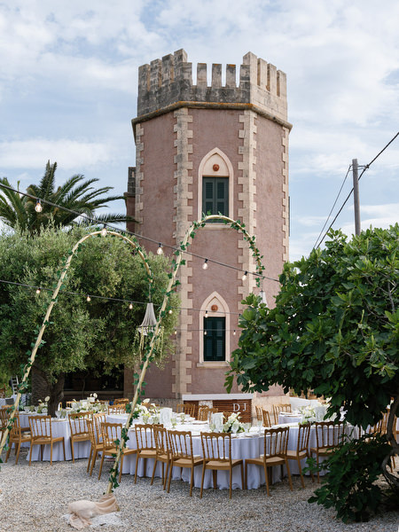 Elegant outdoor reception tables arranged beside the historic Pyrgos Ralli tower