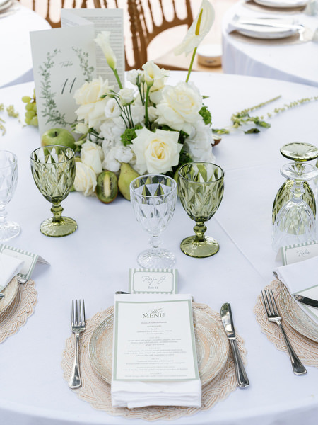Elegant place setting with white florals and green glassware at a Pyrgos Ralli wedding