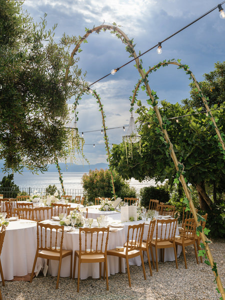 Seaside wedding dinner setup beneath string lights at Pyrgos Ralli in Aegina