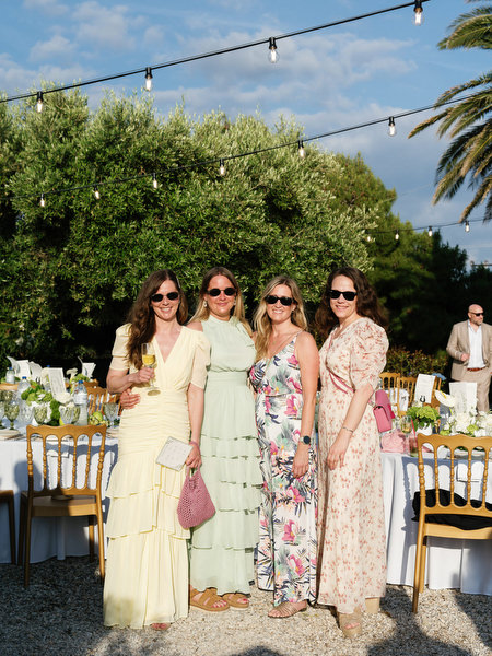 Stylishly dressed wedding guests posing together at the outdoor reception