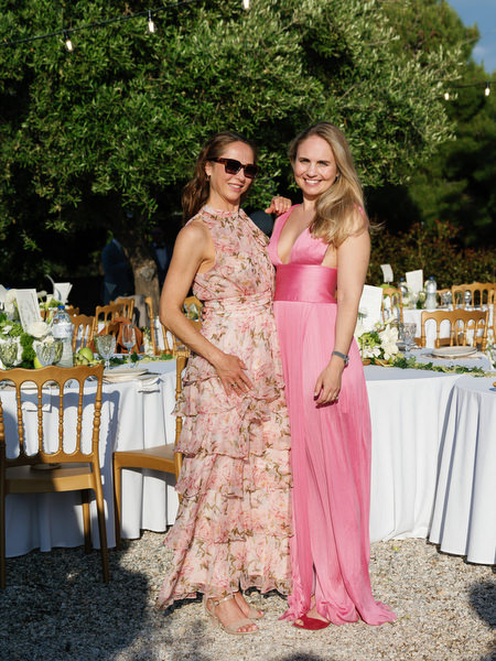 Two wedding guests smiling together beside the reception tables at Pyrgos Ralli