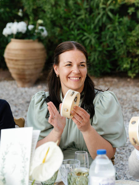 Bridesmaid smiling and holding a handheld fan during the summer wedding reception