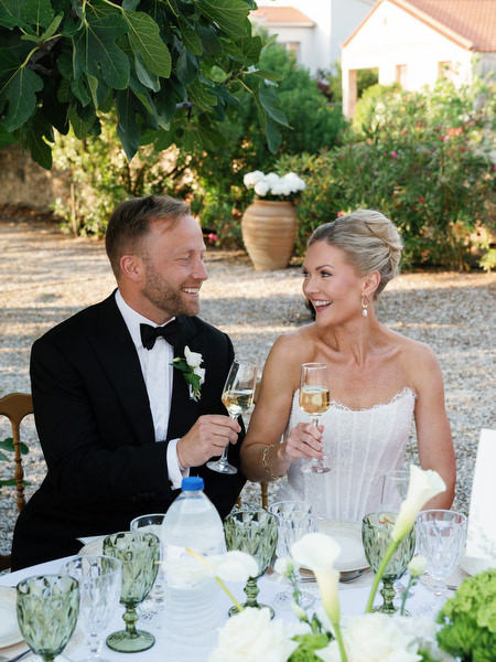 Bride and groom smiling together at their reception table in Aegina