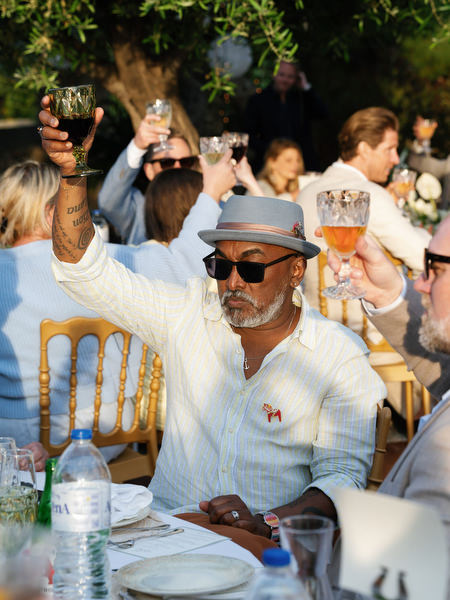 Wedding guest raising a glass during a lively outdoor reception in Aegina