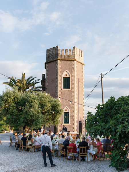 Historic Pyrgos Ralli tower rising above the outdoor wedding reception in Aegina