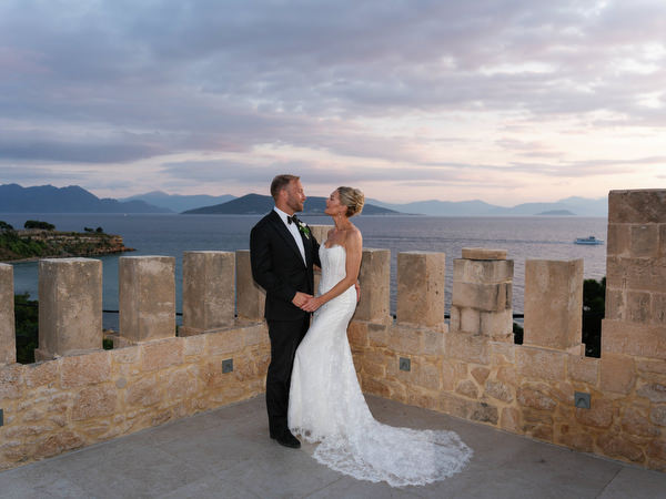 Bride and groom embracing on a stone terrace overlooking the sea in Aegina
