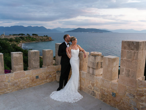 Bride and groom embracing on the stone terrace with sea views in Aegina