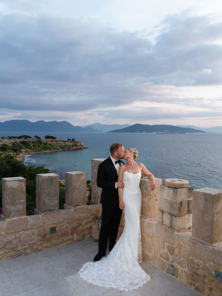 Newlyweds posing on the terrace overlooking the Saronic Gulf at Pyrgos Ralli