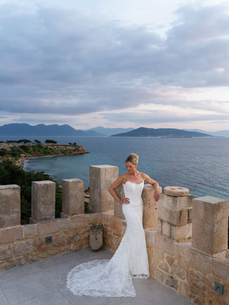 Bride posing against the stone terrace with the sea stretching behind her