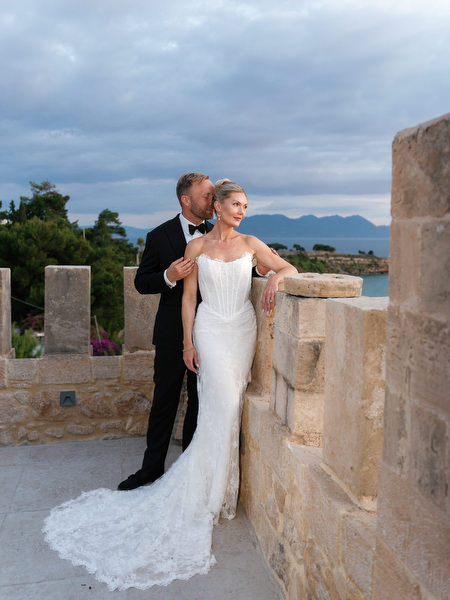 Romantic portrait of the newlyweds beside the stone walls overlooking the sea