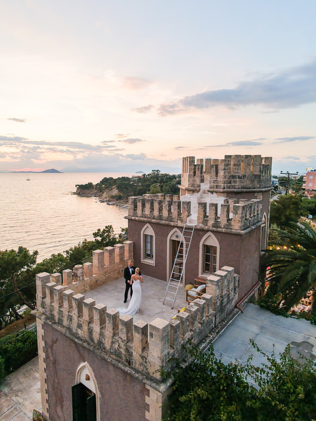 Bride and groom photographed on the historic Pyrgos Ralli tower at sunset
