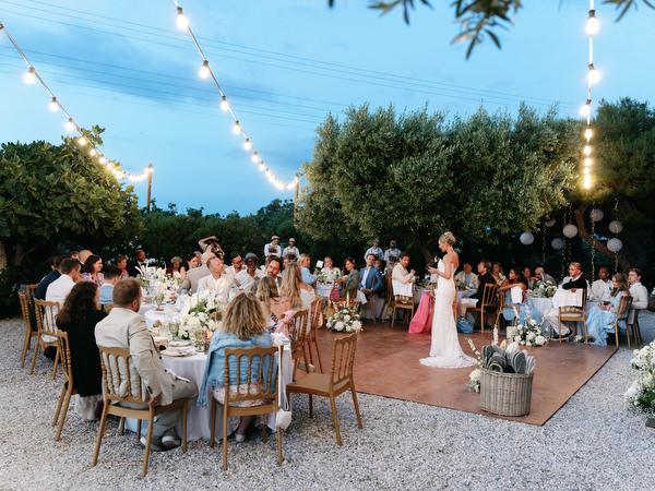 Wedding guests dining outdoors beneath string lights at Pyrgos Ralli in Aegina