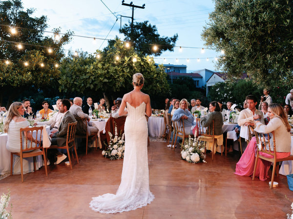 Bride standing during the evening reception as guests gather around her