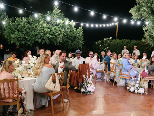 Wedding guests gathered beneath string lights during the evening reception in Aegina