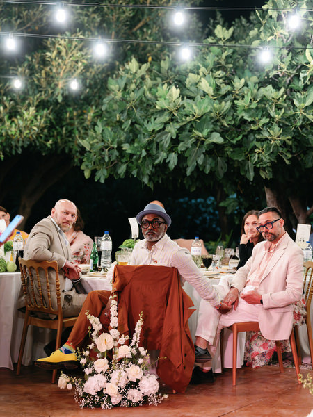 Guests laughing together beneath string lights during the outdoor wedding dinner