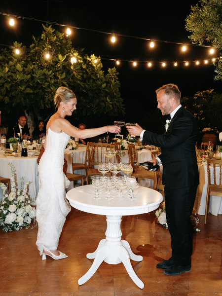 Bride and groom celebrating beside the wedding cake during the evening reception