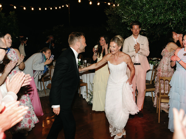 Newlyweds dancing surrounded by friends during their open-air Greek island party