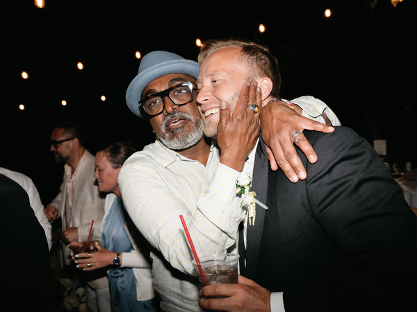 Two wedding guests embracing and smiling during the late-night party in Aegina